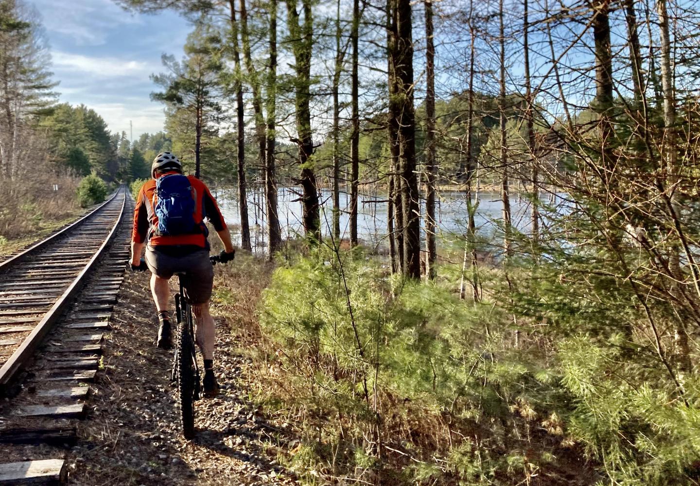 A cyclist rides alongside the rails before they were taken up along the Adirondack Rail Trail