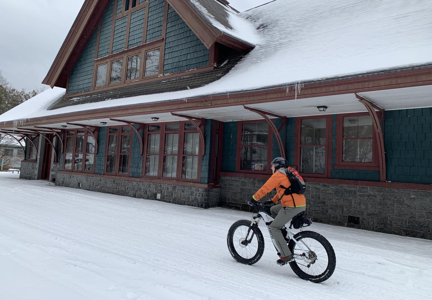 A cyclist rides a fat bike past the depot in Saranac Lake. 