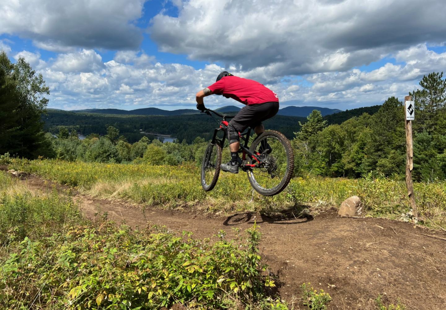 A mountain biker catches a bit of air at the top of the Paint It Black Trail on Mount Sabattis. 