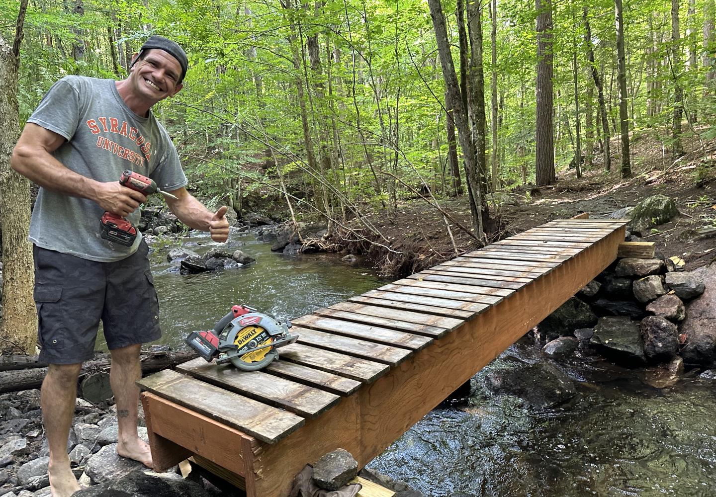 Adam Whitman, a volunteer with the St. Lawrence County Mountain Bike Association, rebuilds a bridge over O’Malley Brook that was wiped out in a summer deluge.