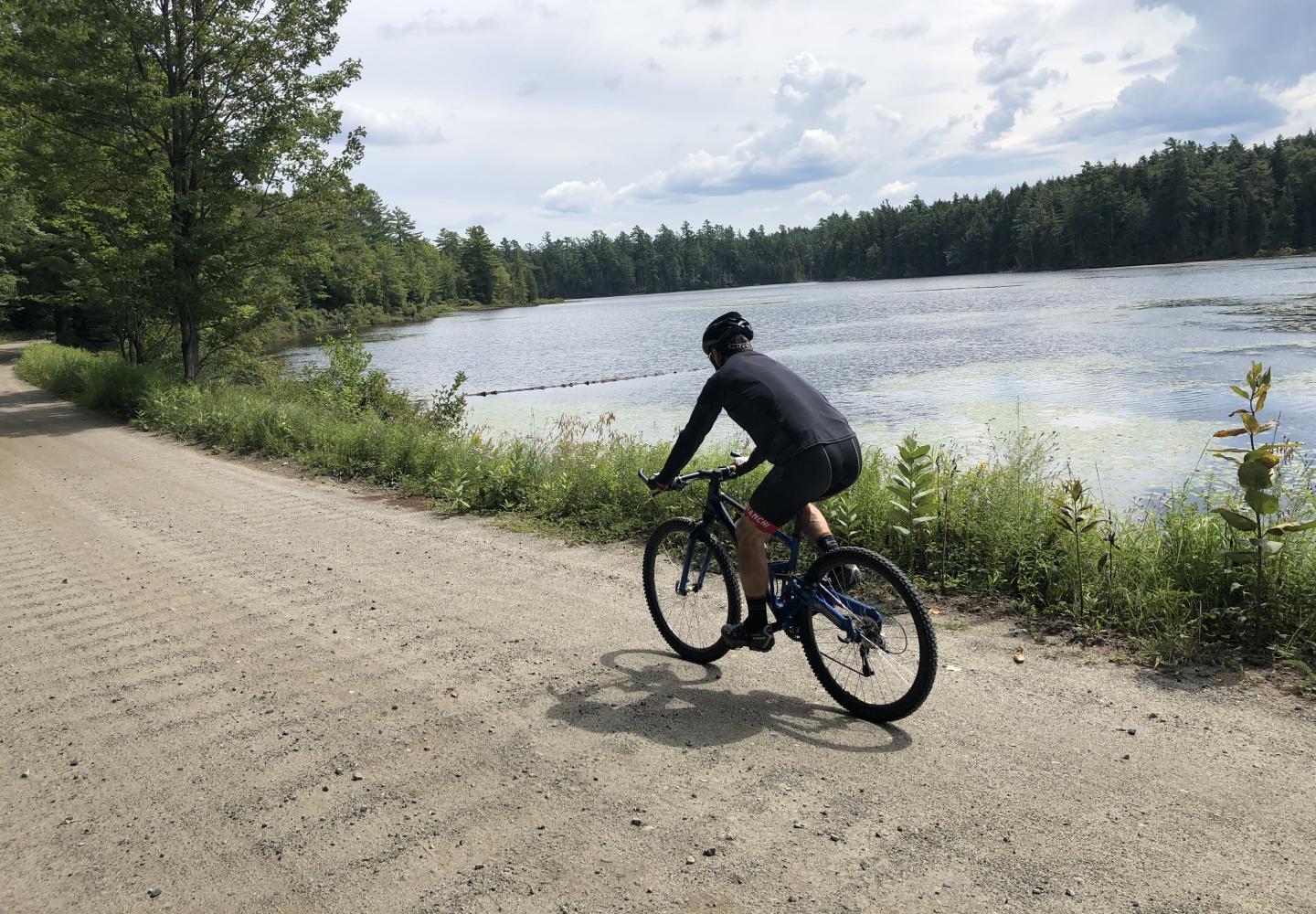 A cyclists passes Middle Pond on Floodwood Road in the Adirondacks.