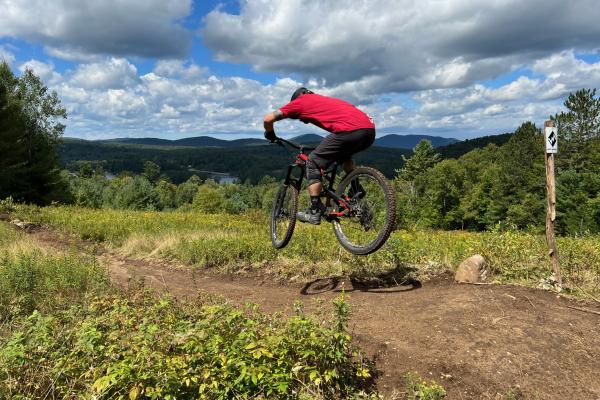 A mountain biker catches a bit of air at the top of the Paint It Black Trail on Mount Sabattis. 