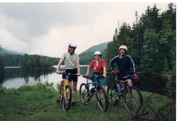 Mountain bikers pose by a wilderness pond in the Adirondacks
